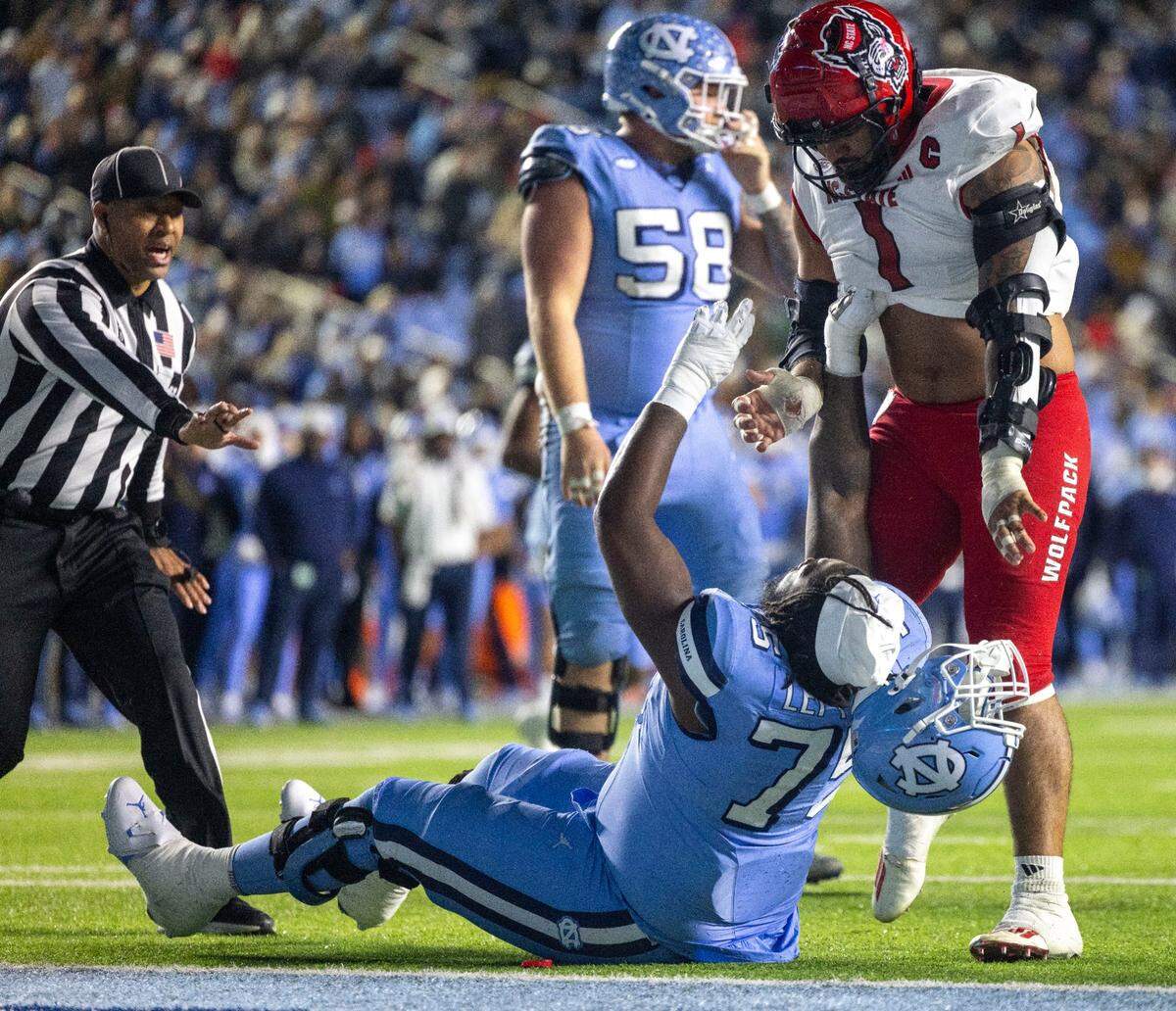 N.C. State defensive end Davin Vann (1) removes the helmet of North Carolina’s Jakiah Leftwich (75) during a scuffle in the fourth quarter on Saturday, November 30, 2024 at Kenan Stadium in Chapel Hill, N.C.