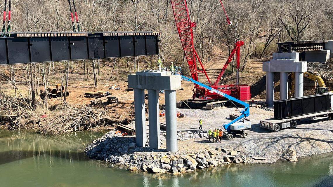 Workers maneuver a steel beam into place for a bridge to carry Norfolk Southern trains over the Pigeon River in Newport, Tennessee, the second week of March 2025. The old bridge was destroyed by flooding from the remnants of Hurricane Helene in September, and replacing it is a key part of reopening the rail line between Tennessee and Asheville, North Carolina.