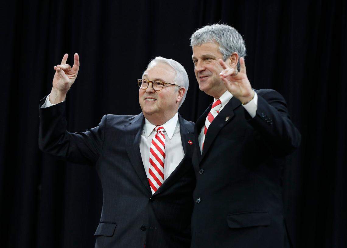 N.C State chancellor Randy Woodson, left, and Athletic Director Boo Corrigan give the Wolfpack sign.