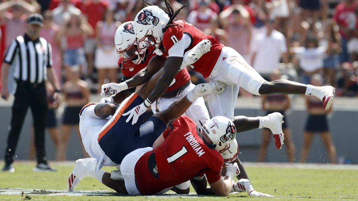 N.C. State’s Caden Fordham (1) and Sean Brown (0) tackle Virginia tight end Dakota Twitty (9) during the first half of N.C. State’s game against Virginia at Carter-Finley Stadium in Raleigh, N.C., Sat. Sept. 6, 2025.