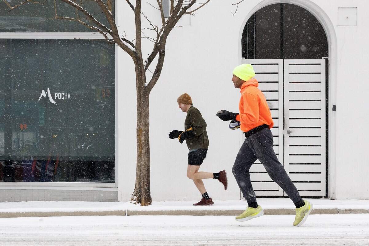 People run along Chapel Hill Street as snow falls on Saturday, Jan. 31, 2026, in downtown Durham, N.C.