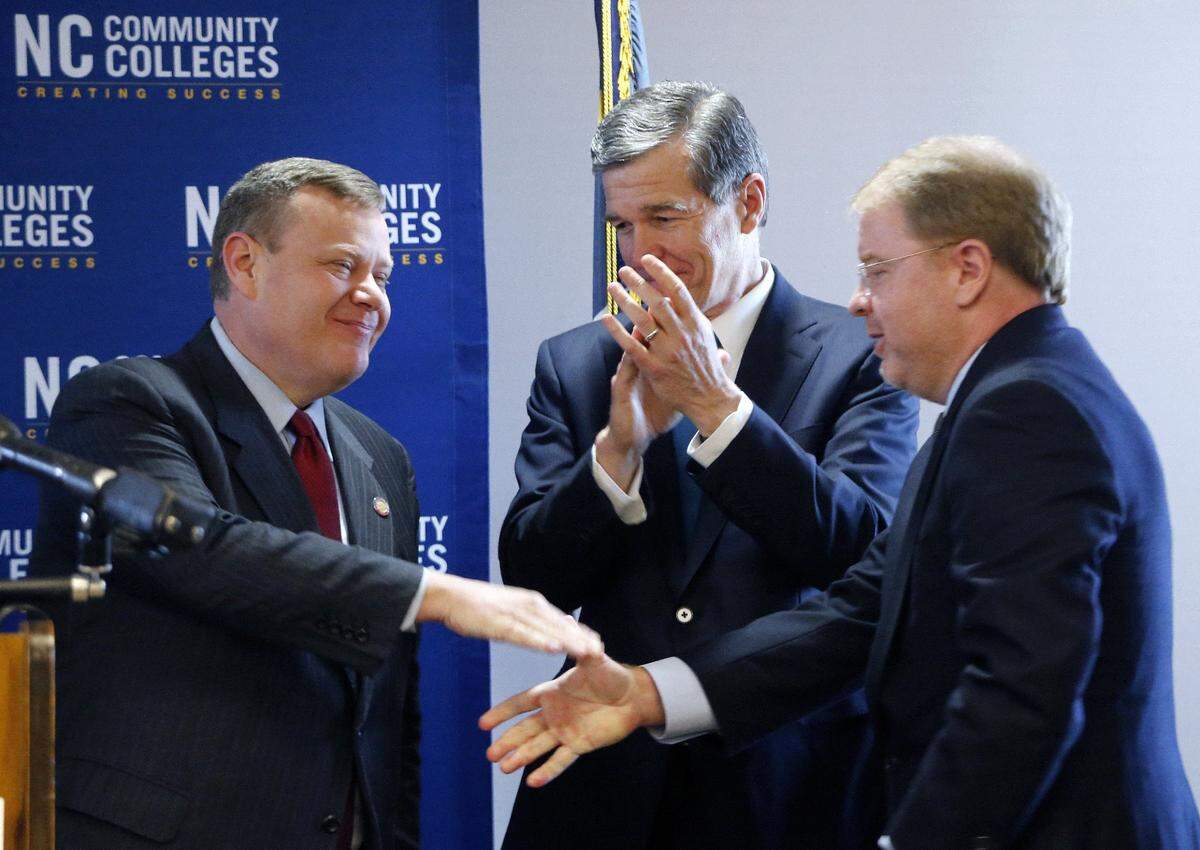Speaker of the House Tim Moore, left, and Governor Roy Cooper, center, congratulate Peter Hans after Hans was named the president of the state Community Colleges system at a press conference at the Community Colleges offices in Raleigh, NC, on Tuesday, May 1, 2018. Hans later went on to be named head of the UNC system.