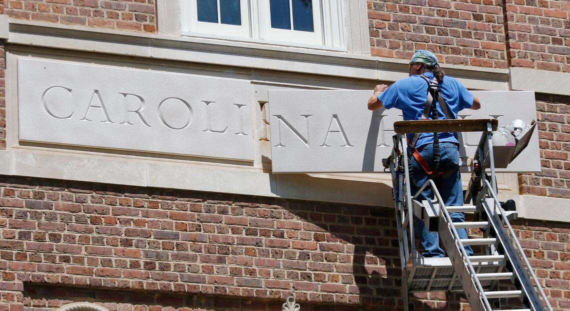 Sign installer Roger Phillips of Broach Custom Signs in Wendell, NC carefully places the second and last urethane panel into place for the new Carolina Hall nameplate Thursday afternoon, August 13, 2015 covering the old Saunders Hall name on the UNC-CH campus. After an outcry over the personal history of the 19th century UNC alumnus William L. Saunders the university decided recently to change the name to Carolina Hall, removing all vestiges of the old name.