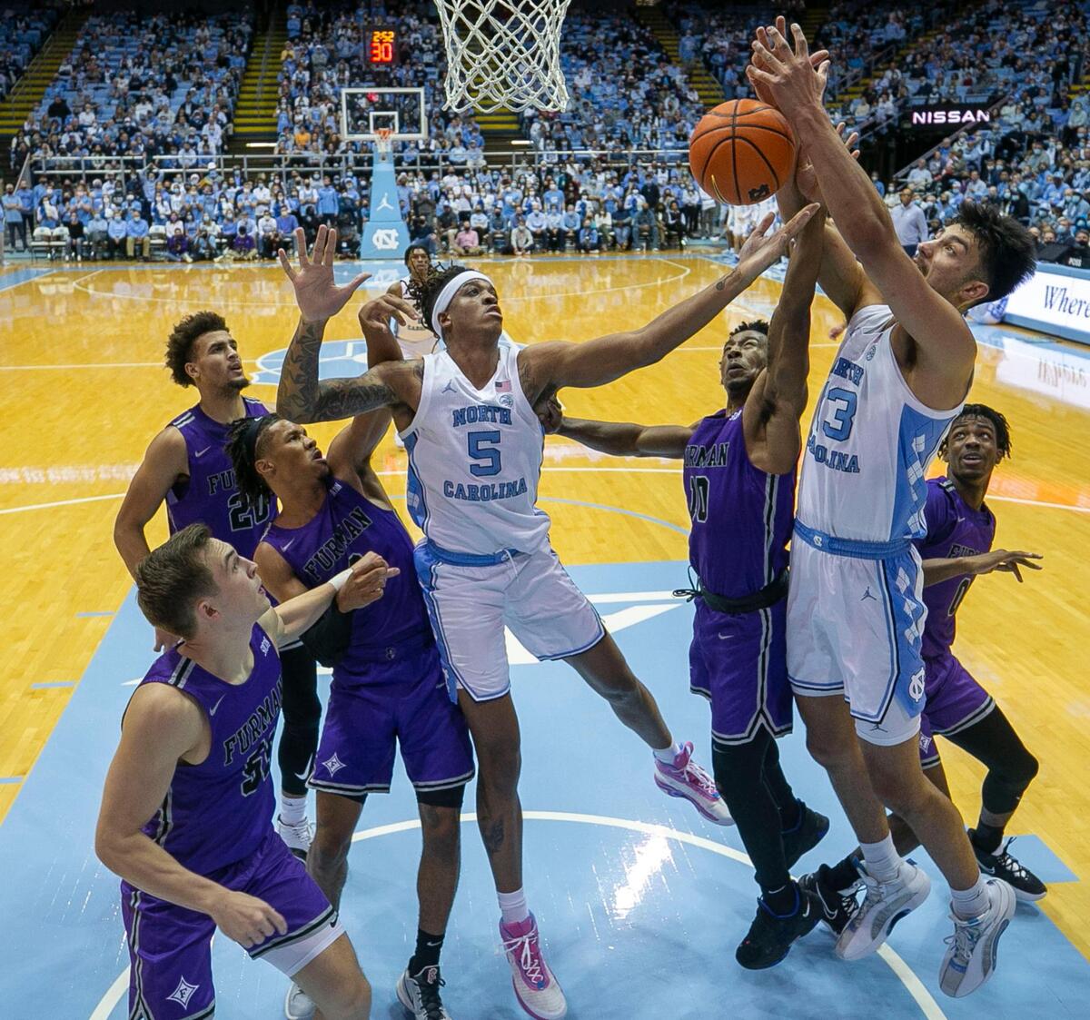 North Carolina’s Dawson Garcia (13) and Armando Bacot (5) crash the boards for an offensive rebound during the first half against Furman on Tuesday, December 14, 2021 at the Smith Center in Chapel Hill, N.C.