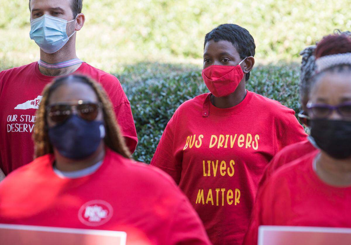Wake County bus drivers Jennifer Jones, middle, and Zac Campbell, left, listen to speakers during a press conference at the General Assembly in Raleigh, N.C. on Friday, Sept. 10, 2021 addressing bus driver shortages.