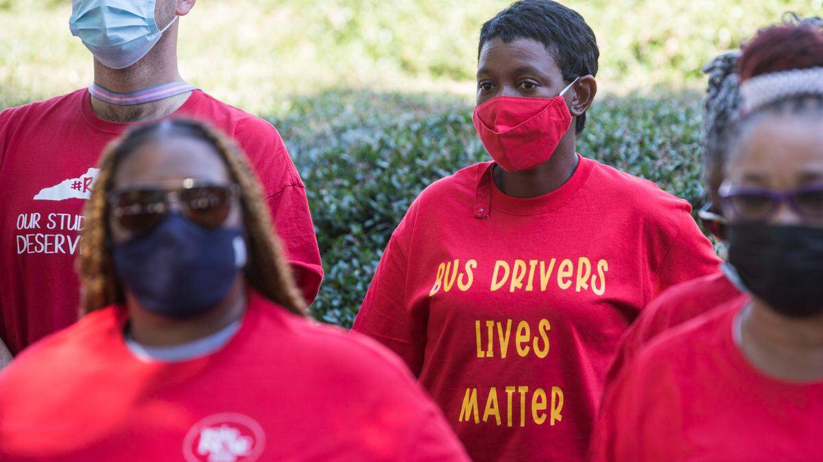 Wake County bus drivers Jennifer Jones, middle, and Zac Campbell, left, listen to speakers during a press conference at the General Assembly in Raleigh, N.C. on Friday, Sept. 10, 2021 addressing bus driver shortages.
