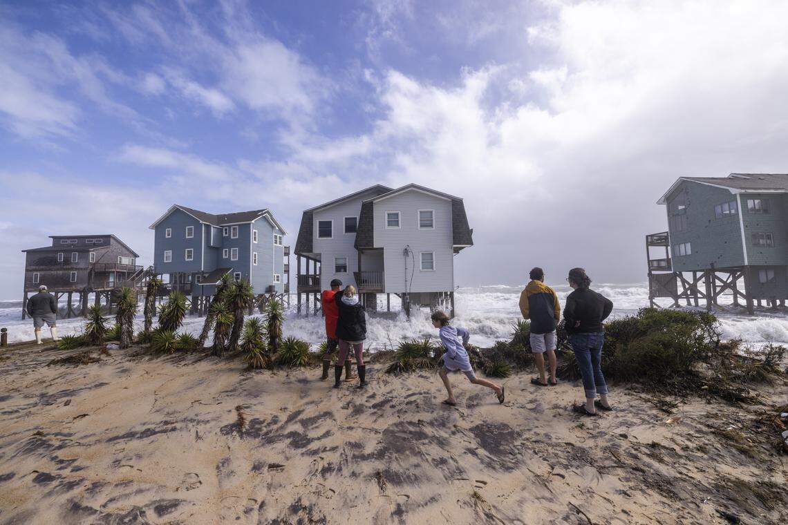 Onlookers watch as rough surf pounds beach homes during high tide on Sunday, Oct. 12, 2025, in Buxton during a nor’easter. Nine homes in the community have collapsed into the Atlantic Ocean since mid-September.