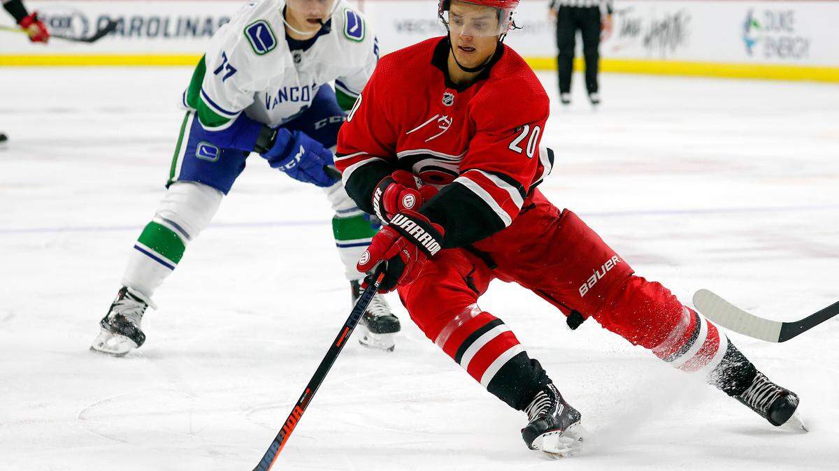 Carolina Hurricanes’ Sebastian Aho (20) gathers in the puck in front of Vancouver Canucks’ Nikolay Goldobin (77) during the second period of an NHL hockey game, Tuesday, Oct. 9, 2018, in Raleigh, N.C. 