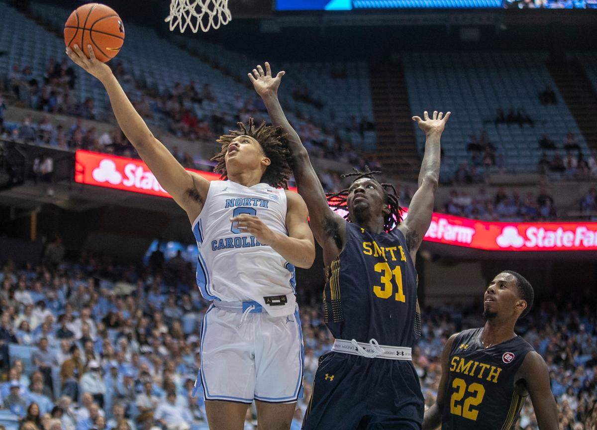 North Carolina’s Seth Trimble (0) drives to the basket against Johnson C. Smith’s Kevin Boykin (31) and Javon Floyd (22) in the first half during an exhibition game on Friday, October 28, 2022 at the Smith Center in Chapel Hill, N.C. Trimble scored 11 points.