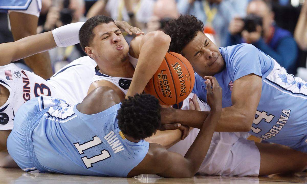 North Carolina’s D’Marco Dunn (11) and Puff Johnson (14) fight for the loose ball with Virginia’s Kadin Shedrick (21) during the first half of UNC’s game against Virginia in the quarterfinals of the ACC Men’s Basketball Tournament in Greensboro, N.C., Thursday, March 9, 2023.