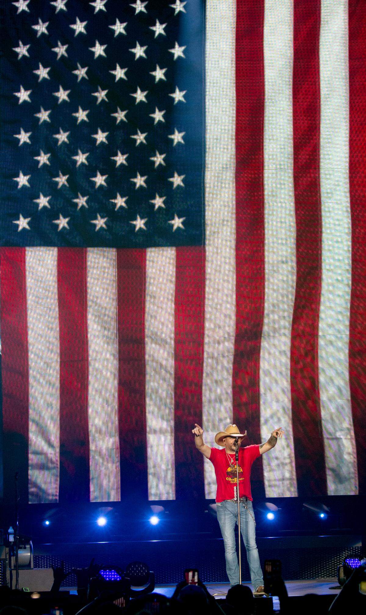 Jason Aldean performs with the U.S. flag as a background during a song at Raleigh, N.C.’s Coastal Credit Union Music Park at Walnut Creek, Friday night, Aug. 11, 2023.