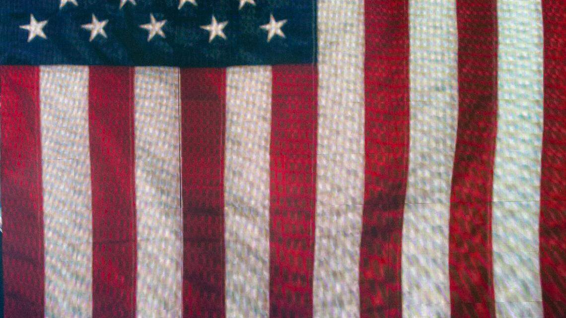 Jason Aldean performs with the U.S. flag as a background during a song at Raleigh, N.C.’s Coastal Credit Union Music Park at Walnut Creek, Friday night, Aug. 11, 2023.