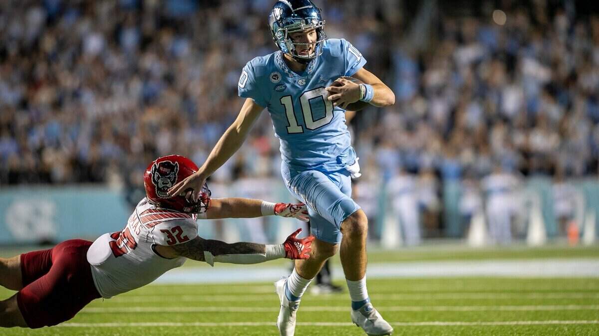 North Carolina quarterback Drake Maye (10) breaks away from N.C. State’s Drake Thomas (32) to score a touchdown on a 14-yard run in the fourth quarter to tie N.C. State 17-17 on Friday, November 25, 2022 at Kenan Stadium in Chapel Hill, N.C.
