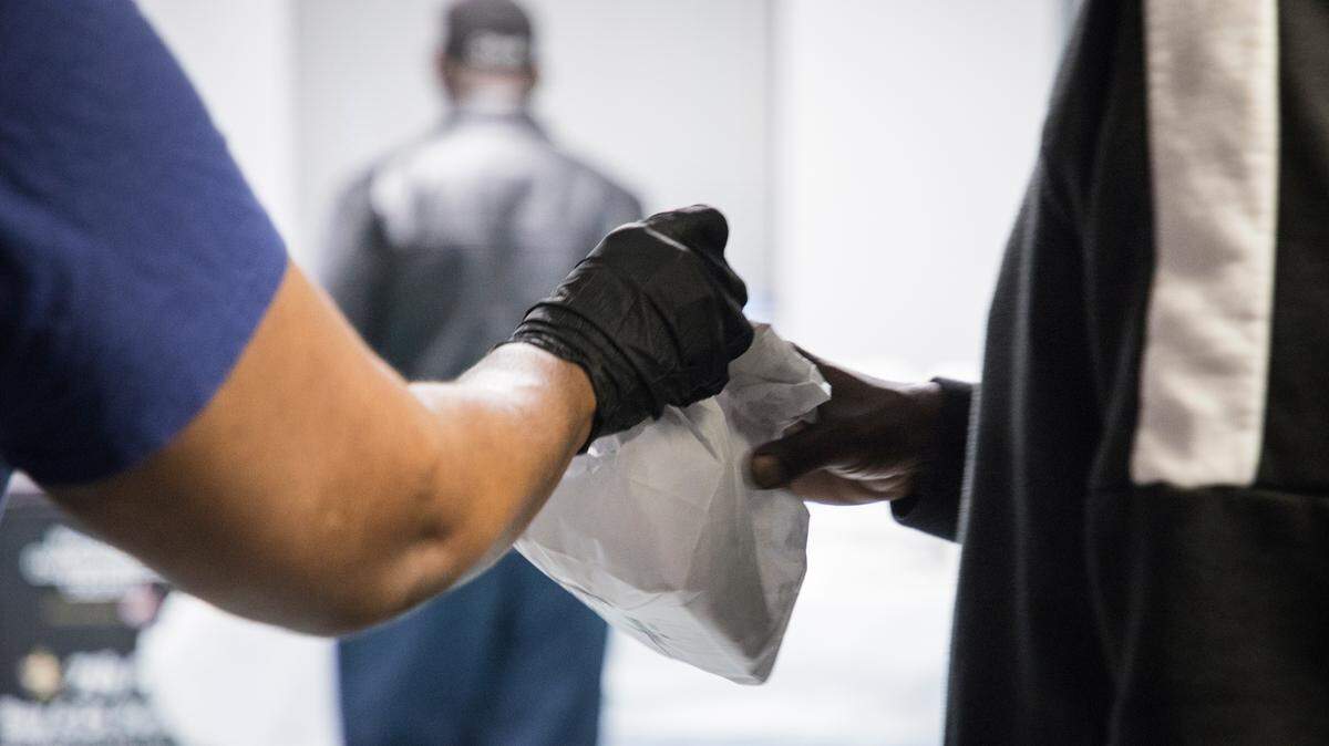 A staff member at Urban Ministries of Durham hands a bagged lunch to an individual who isn’t currently staying in their shelter on Thursday morning, March 19, 2020.