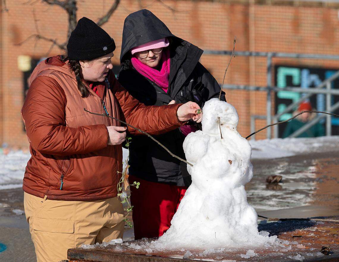 Rebecca Cook and Karie Whitman decorate a snowman in Durham Central Park on Saturday, Jan. 11, 2025.