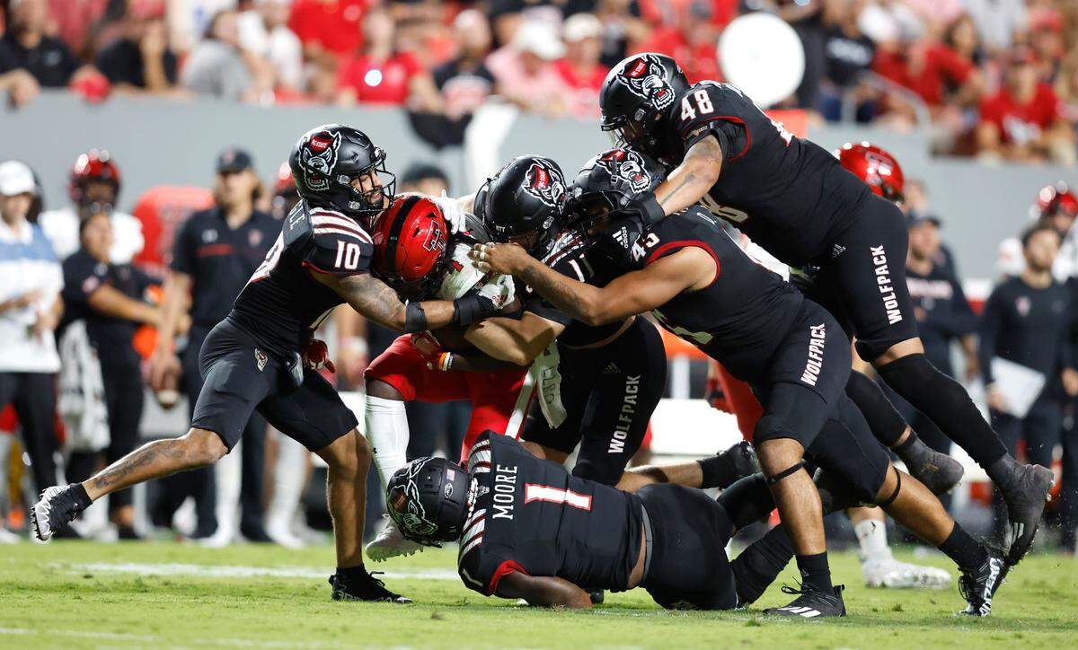 N.C. State’s Tanner Ingle (10), Payton Wilson (11), Isaiah Moore (1), Davin Vann (45), and Cory Durden (48) stop Texas Tech running back SaRodorick Thompson (4) during the second half of N.C. State’s 27-14 victory over Texas Tech at Carter-Finley Stadium in Raleigh, N.C., Saturday, Sept. 17, 2022.