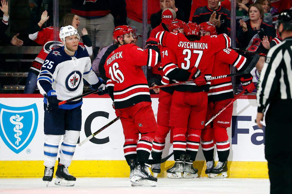 The Carolina Hurricanes celebrate a goal by Jaccob Slavin (74) as Winnipeg Jets’ Paul Stastny (25) skates past during the third period of an NHL hockey game in Raleigh, N.C., Thursday, April 21, 2022. (AP Photo/Karl B DeBlaker)