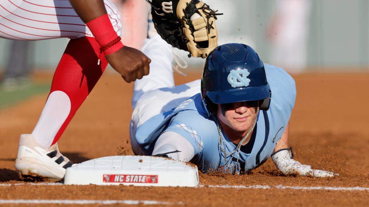 North Carolina’s Mac Horvath slides safely back to first as N.C. State’s LuJames Groover III applies the tag during a game at Doak Field in Raleigh on May 6, 2022. On Sunday, Horvath hit a home run in the bottom of the ninth inning of an elimination game against Iowa in the 2023 NCAA Tournament’s Terre Haute Regional.