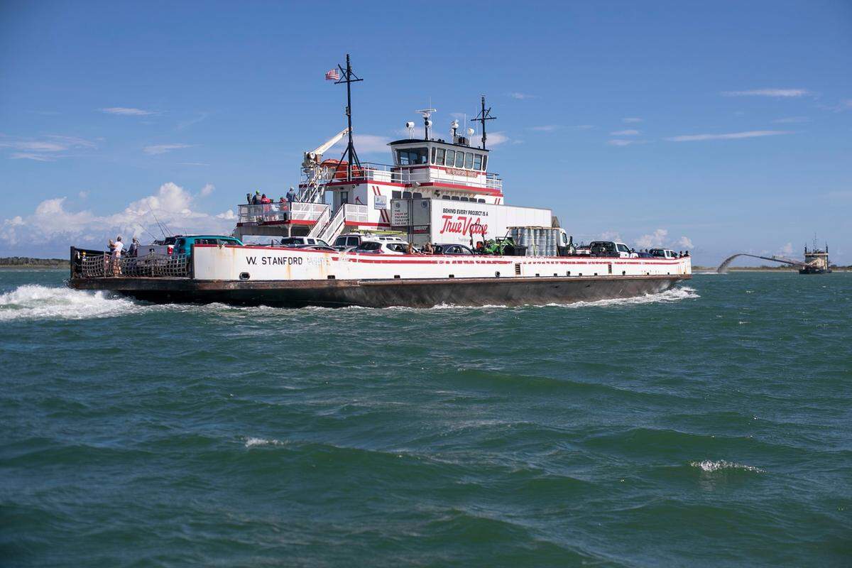 The W. Stanford White Ferry carries passengers from Hatteras Village to Ocracoke Island past a dredging operation in the channel on June 30, 2021.