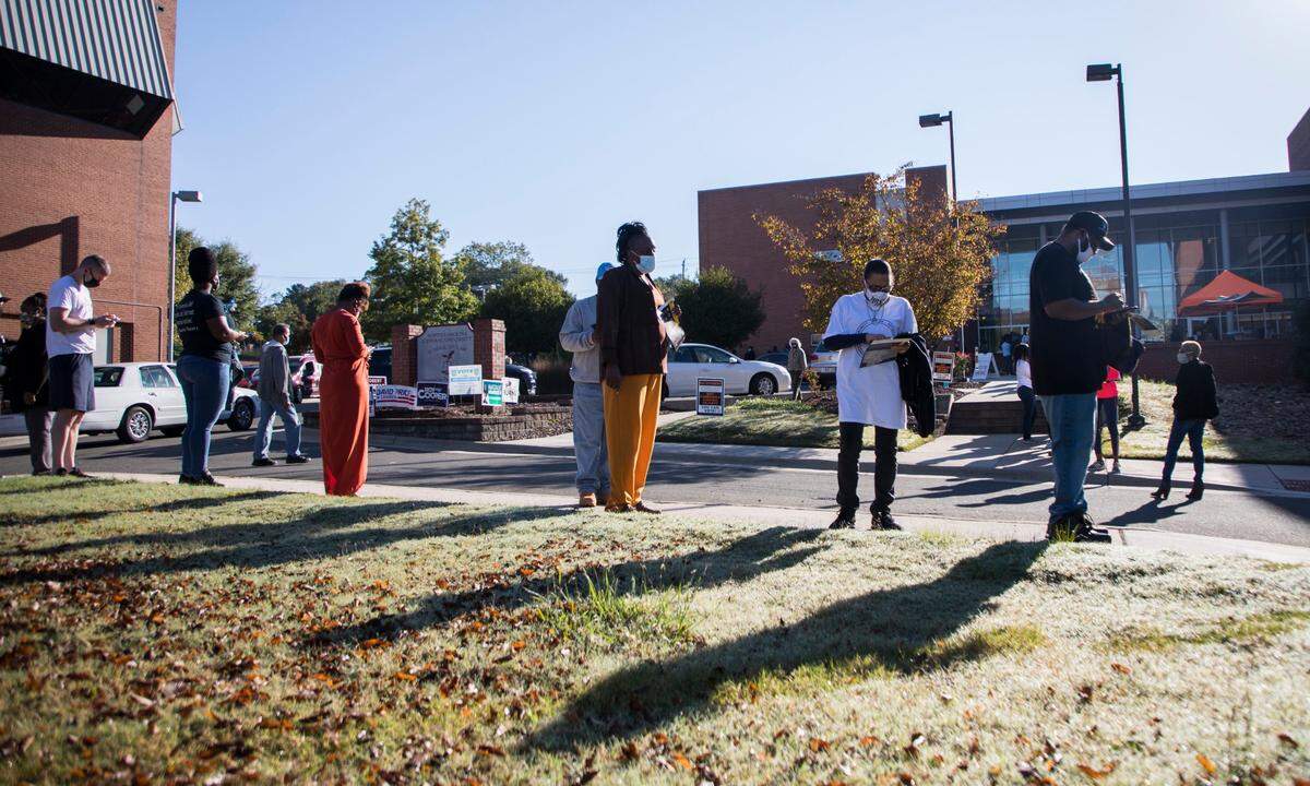 Durham County voters wait in line outside the Turner Law Building at N.C. Central University in Durham, N.C. to cast their votes on the first day of early voting, Thursday, Oct. 15, 2020.