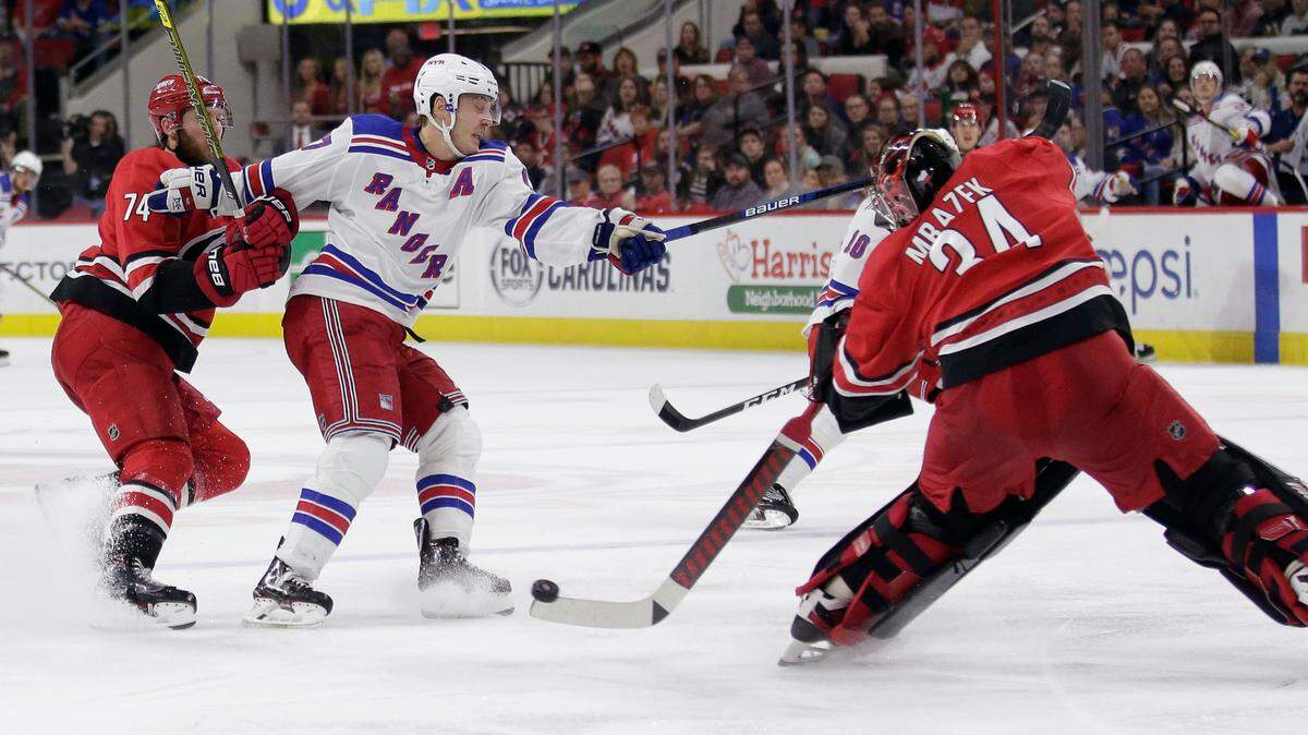 FILE - In this Nov. 7, 2019, file photo, Carolina Hurricanes goaltender Petr Mrazek (34), of the Czech Republic, blocks New York Rangers right wing Jesper Fast, of Sweden, with Hurricanes defenseman Jaccob Slavin (74) slowing Fast during the third period of an NHL hockey game in Raleigh, N.C. Carolina was one of two teams (along with Tampa Bay) that voted against the current playoff format, which doesn’t reward it for being in a playoff spot when the season was paused. But the Hurricanes shouldn’t need emergency goaltender David Ayres anymore with Mrazek and James Reimer healthy in net. (AP Photo/Gerry Broome, File)