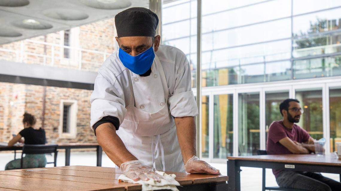Staff member Munwar Ahmad wears a mask while sanitizing surfaces on campus at Duke University on Tuesday, Sept. 1, 2020, in Durham, N.C.