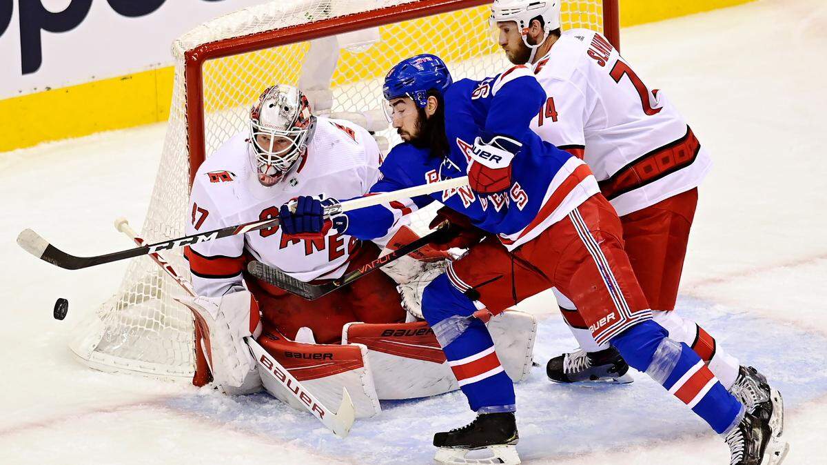New York Rangers’ Mika Zibanejad (93) tries to tip a puck in front of Carolina Hurricanes’ goaltender James Reimer (47) as Hurricanes’ Jaccob Slavin (74) defends during first period NHL Eastern Conference Stanley Cup playoff action in Toronto on Tuesday, Aug. 4, 2020. (Frank Gunn/The Canadian Press via AP)
