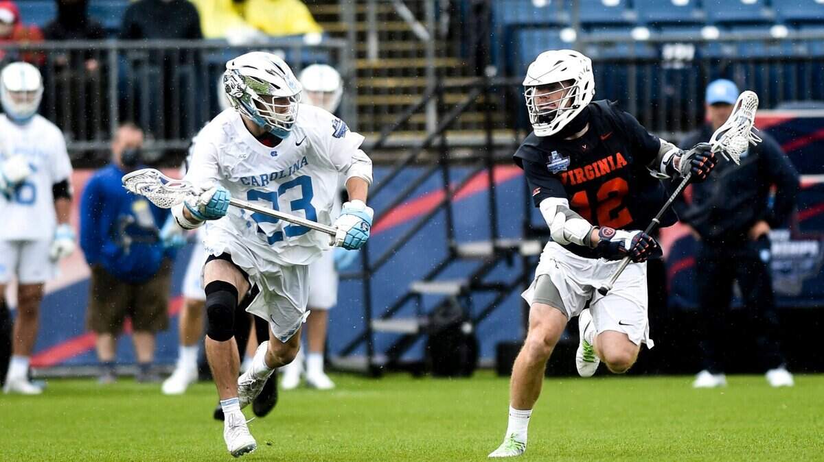 Virginia’s Jack Simmons (12) is guarded by North Carolina’s Parker Alexander (23) during the semifinals of men’s NCAA Division I college lacrosse tournament at Pratt & Whitney Stadium at Rentschler Field Saturday, May 29, 2021, in East Hartford, Conn. (Kassi Jackson/Hartford Courant via AP)