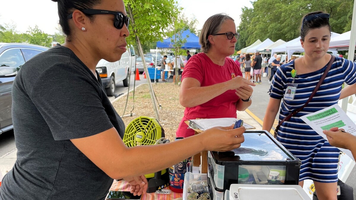 Chapel Hill Farmers’ Market Assistant Manager Tenita Solanto (left) and other staff members answer questions while handing out Double Bucks tokens to a customer at the South Estes Drive market on Tuesday, July 30, 2024.