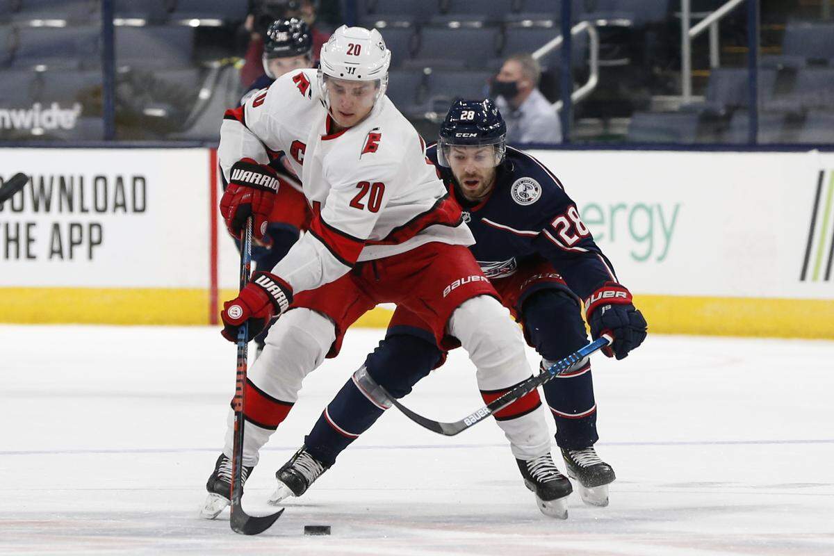 Carolina Hurricanes’ Sebastian Aho, left, carries the puck up ice as Columbus Blue Jackets’ Oliver Bjorkstrand defends during the first period of an NHL hockey game Monday, Feb. 8, 2021, in Columbus, Ohio. (AP Photo/Jay LaPrete)