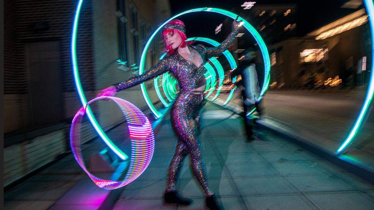 Hoop dancer Paige LaWall performs in the “Sonic Runway” along South Saunders Street in downtown Raleigh Friday, Dec. 2, 2022. The large-scale, interactive light-based art piece is one of 18 installations around downtown Raleigh and the Glenwood South district that make up the Illuminate Art Walk presented by Wake Tech.