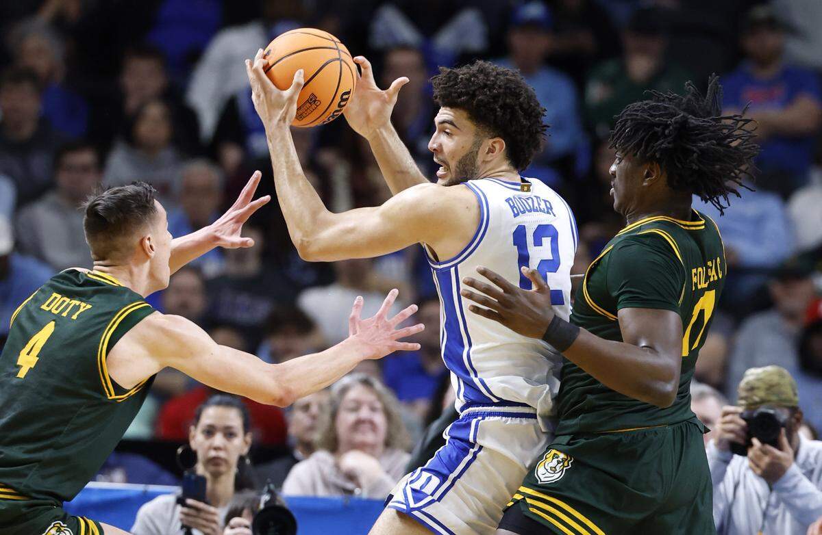 Duke’s Cameron Boozer (12) keeps the ball from Siena's Gavin Doty (4) and Justice Shoats (0) during the first half of Duke’s game against Siena in the first round of the NCAA Men’s Basketball Tournament at  Bon Secours Wellness Arena in Greenville, S.C., Thursday, March 19, 2026.
