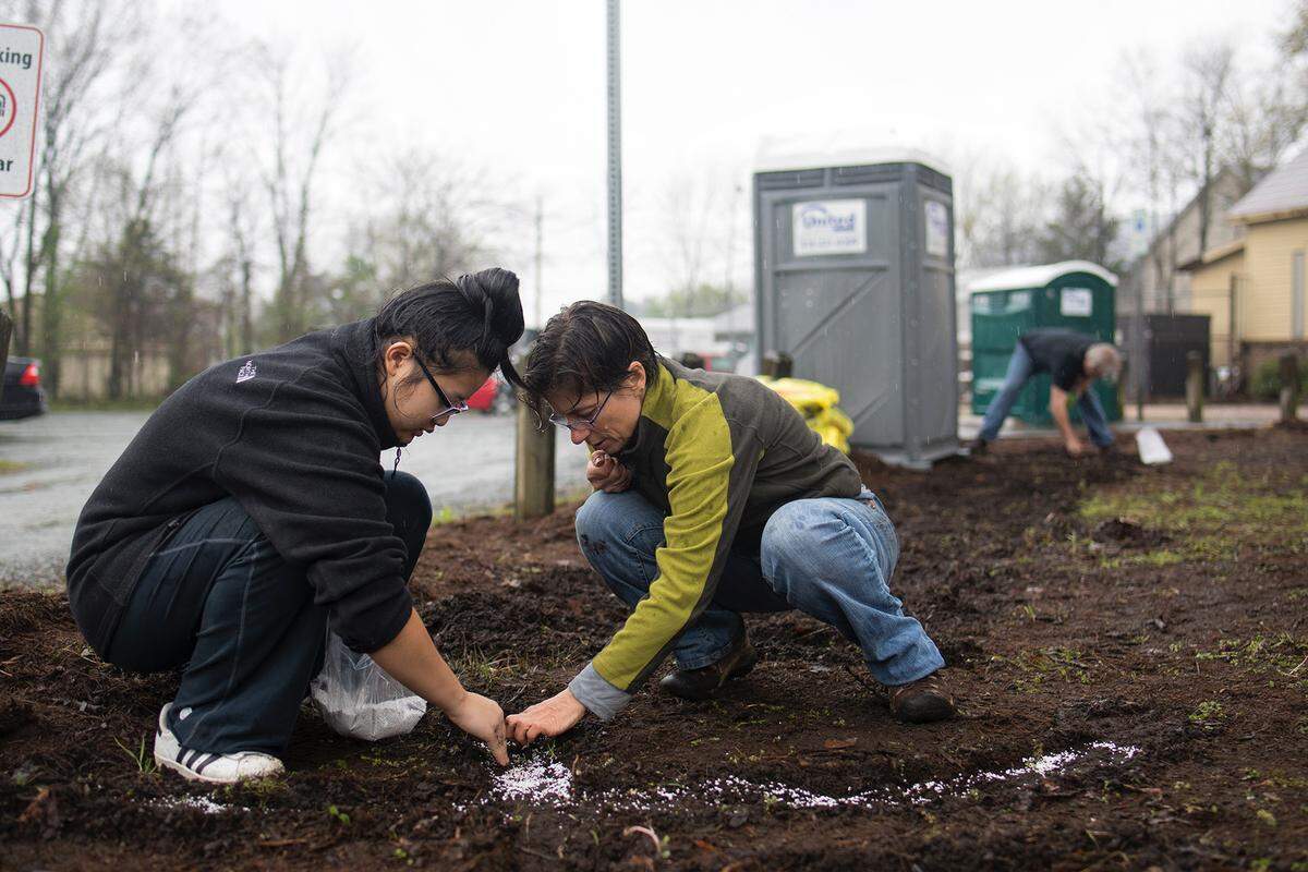 Carter Hubbard, right, plants words in Carrboro with a teen participant in the 2018 Floraffiti project. Hubbard is the founder of the community art program, now in its sixth year in Chapel Hill and Carrboro. On Friday, May 11, participants will perform around their words at the height of the flowers' growth during the 2nd Friday ArtWalk.