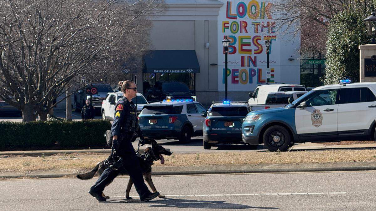 A Raleigh Police officer walks by the scene at North Hills in Raleigh, N.C. after 3 men were shot and 1 killed, Friday, Jan. 17, 2024.