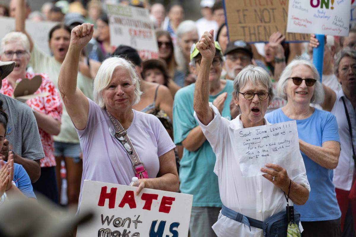 Jean Lapka and Margaret Parjm cheer outside the North Carolina State Legislature in a “good trouble” protest on Thursday, July 17, 2025, the fifth anniversary of John Lewis’s death.