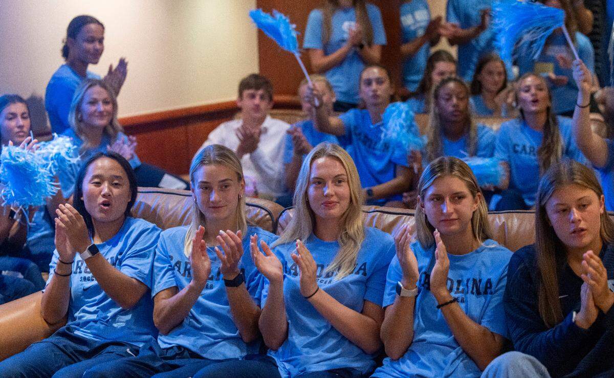 Eden Bretzer, center, a member of the North Carolina women’s soccer team is flanked by her teammates as they applaud the arrival of coach Anson Dorrance to his public retirement announcement on Monday, August 12, 2024 at the Smith Center in Chapel Hill, N.C. Dorrance retires following 45 seasons and 21 NCAA Championships.