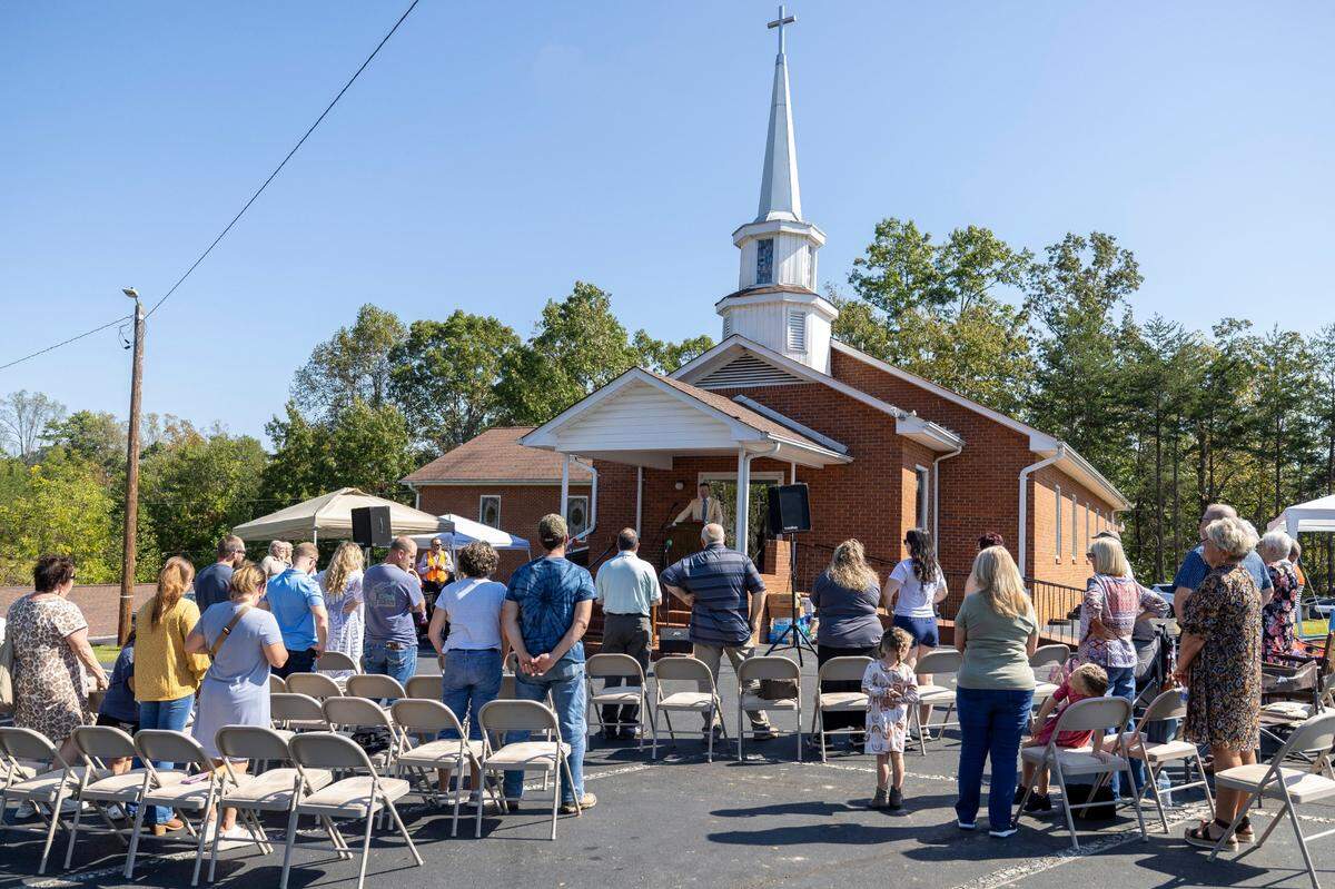 Pastor Austin Bullock presides over services in the parking lot at Salem Free Will Baptist Church on Sunday, October 6, 2024 in Old Fort, N.C. Still without power more than a week after Hurricane Helene, they gathered outside to sing, read scripture and comfort each other.