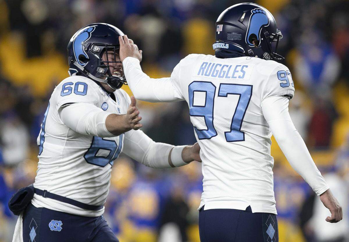 North Carolina kicker Noah Ruggles (97) gives his long snapper Trevor Collins (60) a pat on the head after connecting for a 32-yard field goal to tie Pittsburgh 27-27 and force overtime on Thursday, November 14, 2019 at Heinz Field in Pittsburgh, Pa.