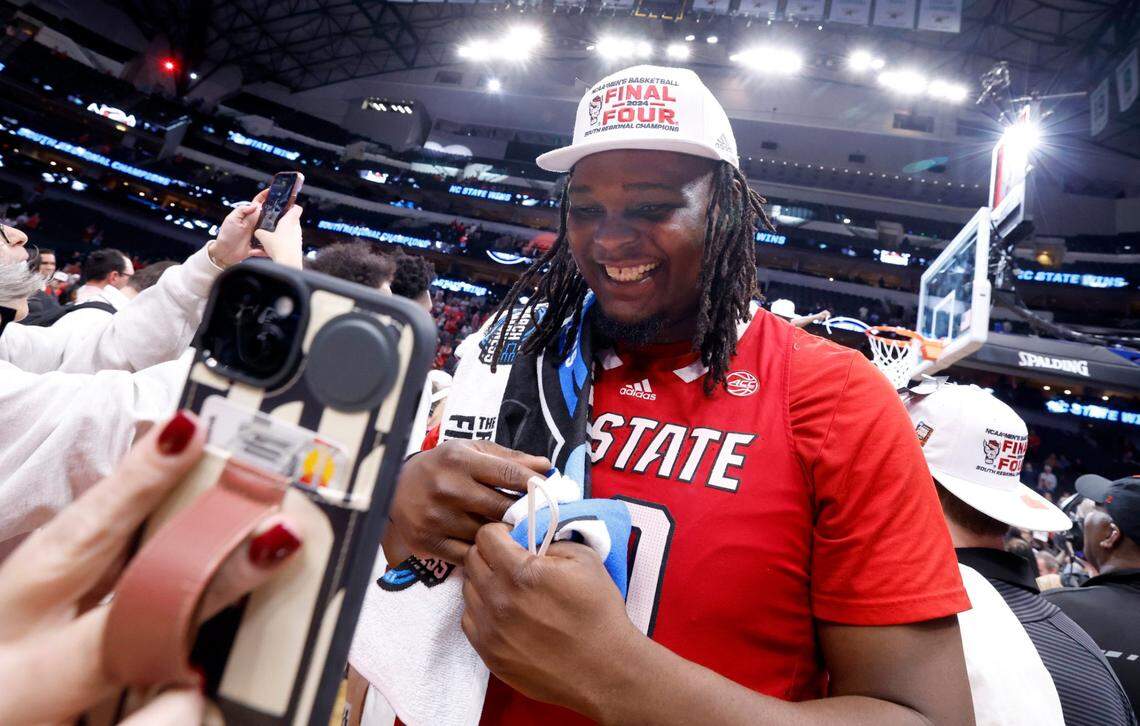 N.C. State’s DJ Burns Jr. (30) FaceTimes with the Wolfpack women’s basketball team after their 76-64 victory over Duke in their NCAA Tournament Elite Eight matchup at the American Airlines Center in Dallas, Texas, Sunday, March 31, 2024.