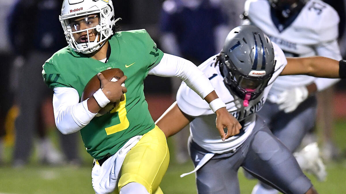 Cardinal Gibbons quarterback Gannon Jones (3) runs for yardage ahead of Hillside’s Jaylen Starks (1) during the first half. The Cardinal Gibbons Crusaders and the Durham Hillside Hornets met in the third round of the NCHSAA 4A playoffs in Raleigh, N.C. on November 29, 2024.