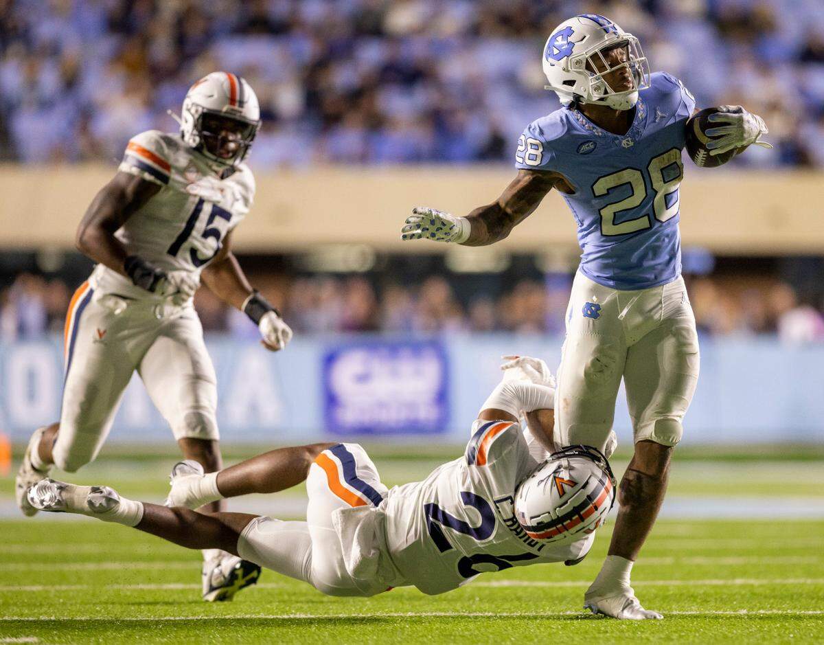 Virginia’s Caleb Hardy (26) works to slow North Carolina running back Omarion Hampton (28) after a pass reception and a gain of 19 yards in the fourth quarter on Saturday, October 21, 2023 at Kenan Stadium in Chapel Hill, N.C.
