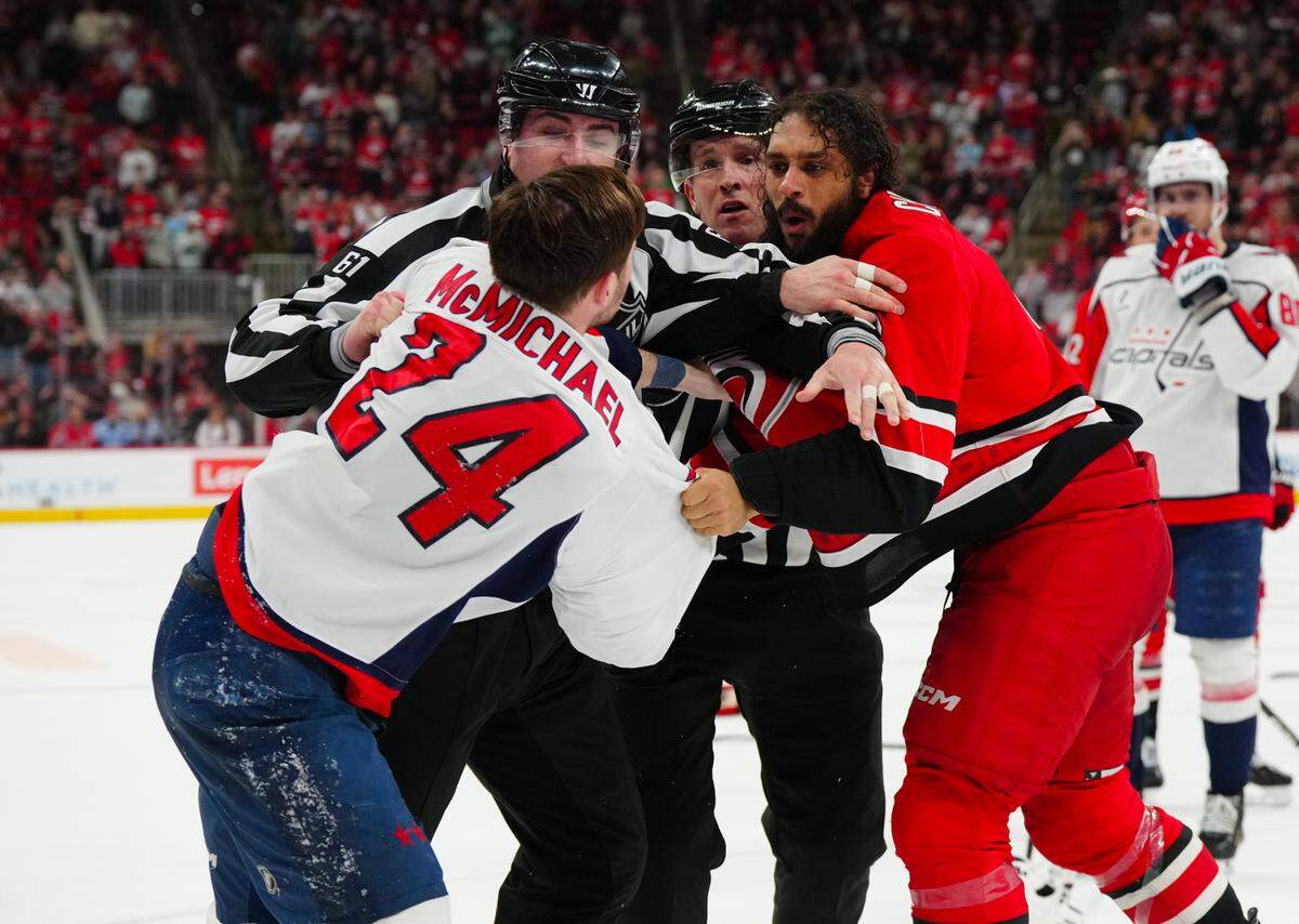 Carolina Hurricanes defenseman Jalen Chatfield (5) and Washington Capitals center Connor McMichael (24) fight during the third period at the Lenovo Center in April.