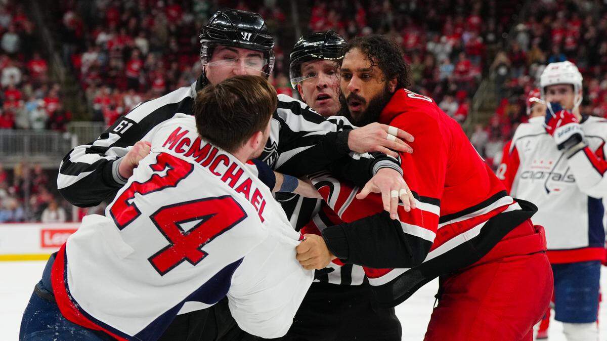 Carolina Hurricanes defenseman Jalen Chatfield (5) and Washington Capitals center Connor McMichael (24) fight during the third period at the Lenovo Center in April.