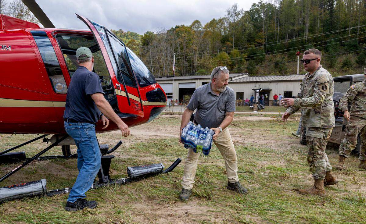 Mark Harrison, Chief Medical Officer for the Pensacola Fire Department, center, unloads supplies from Helicopter pilot Brett James, with Willow Creek Aviation of Louisburg, N.C., on Thursday, October 3, 2024 in Pensacola, N.C.