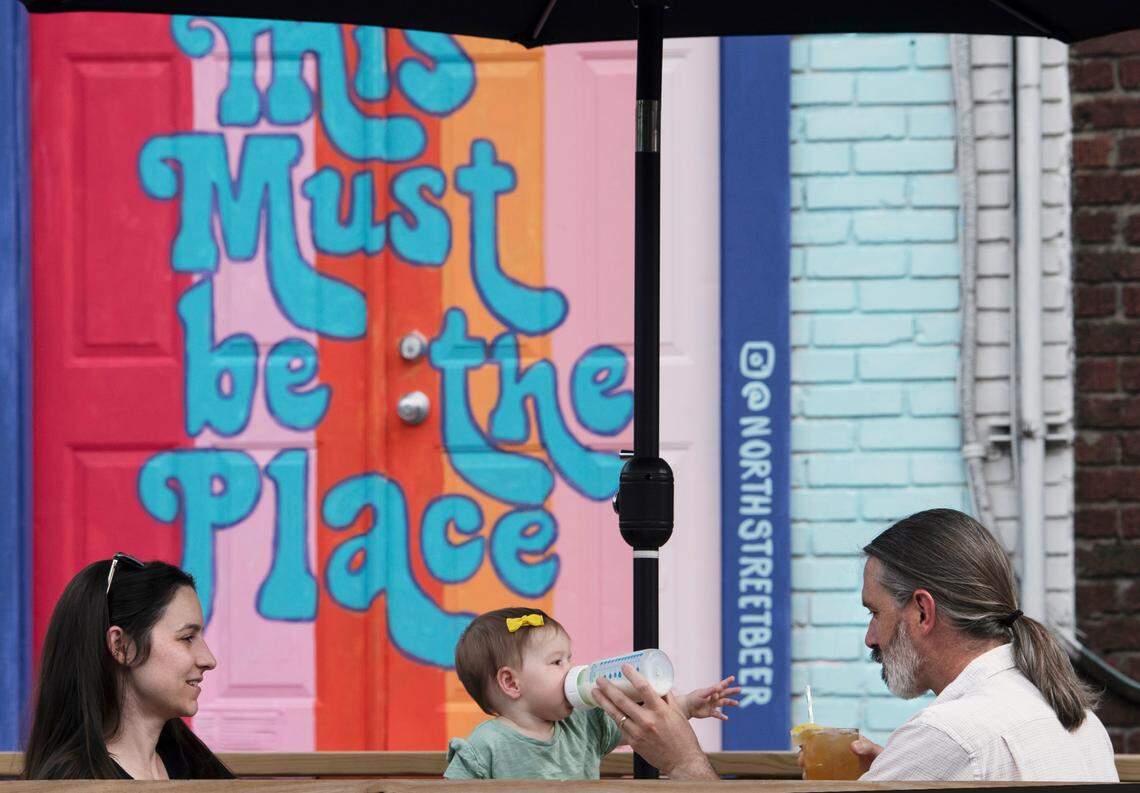 Megan Neal looks on as husband Todd Neal (right) gives 9-month-old daughter Hazel a bottle as they have dinner in Glenwood South at 4:54 pm.
