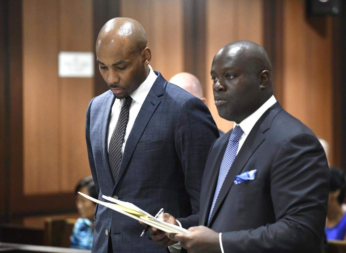 In this Thursday, Aug. 9, 2018, photo, Jamill Jones, left, appears in Queens Criminal Court in New York. The parents of a Florida man who died after he was punched by Jones, an assistant basketball coach at Wake Forest University, said Friday they don’t accept the coach’s condolences.