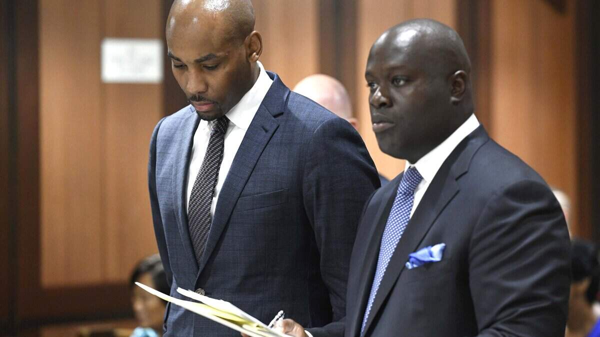 In this Thursday, Aug. 9, 2018, photo, Jamill Jones, left, appears in Queens Criminal Court in New York. The parents of a Florida man who died after he was punched by Jones, an assistant basketball coach at Wake Forest University, said Friday they don’t accept the coach’s condolences.