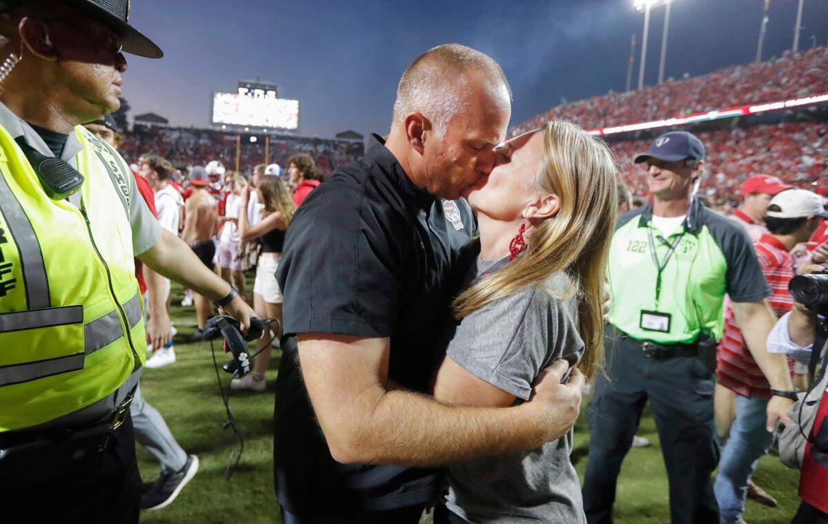 N.C. State head coach Dave Doeren kisses his wife Sara after the Wolfpack’s 27-21 overtime victory over Clemson at Carter-Finley Stadium in September 2021.