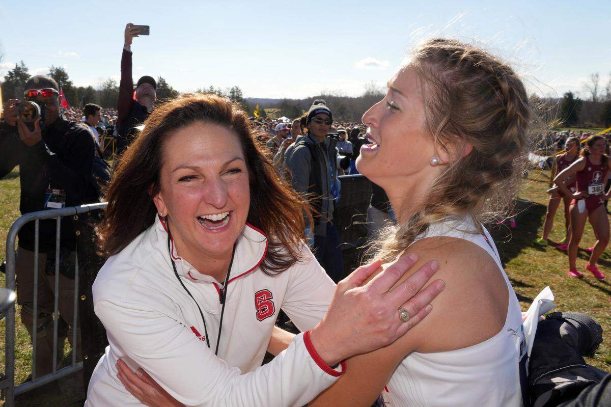 NC State coach Laurie Henes (left) and Amaris Tyynismaa celebrate after the Wolfpack won the women’s team title during the NCAA cross country championships at Panorama Farms.