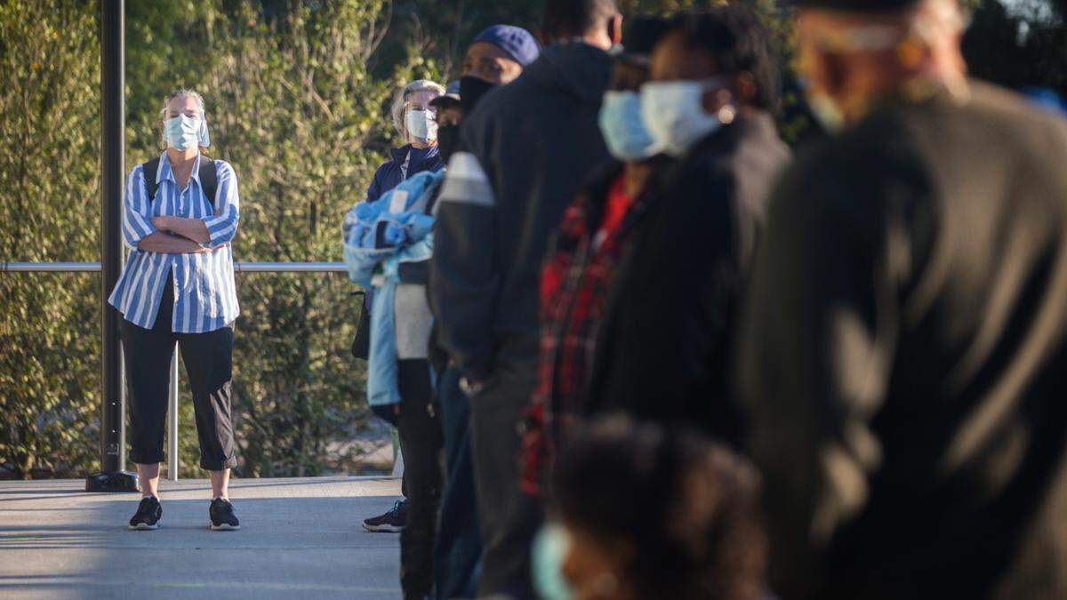 Brooke Whiteford, left, wears a face shield while waiting in line to vote outside the Durham County Main Library in Durham, N.C. on Thursday, Oct. 15, 2020, the first day of early voting.